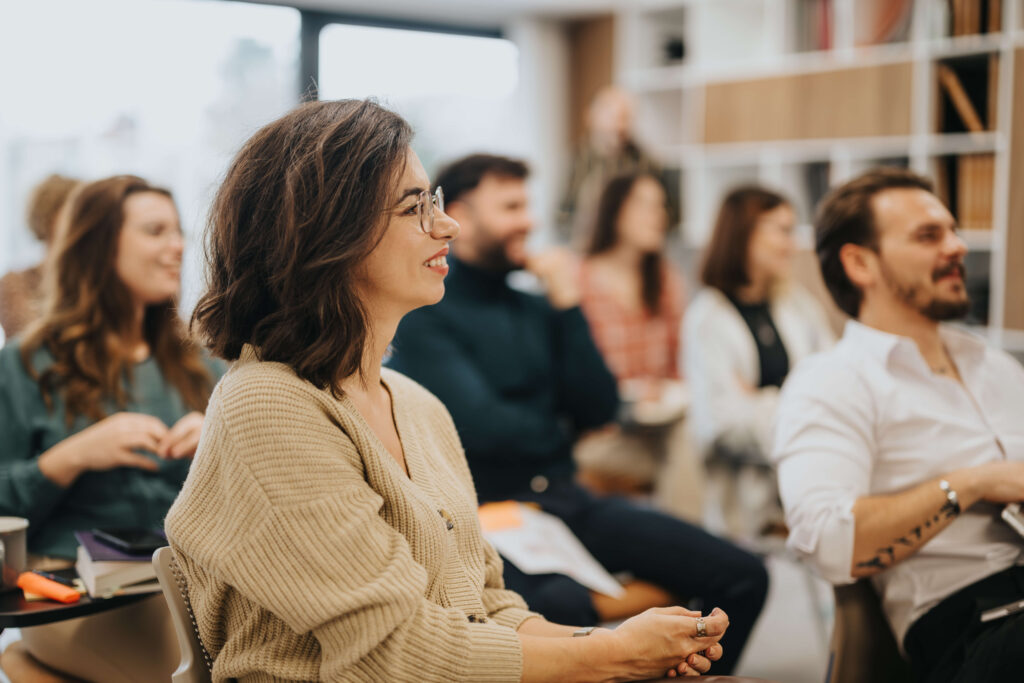 Woman sitting in a conference room smiling at the speaker