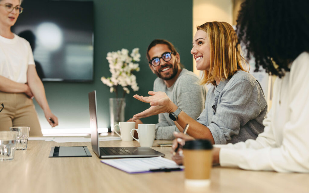 woman sitting at a conference room desk with coworkers