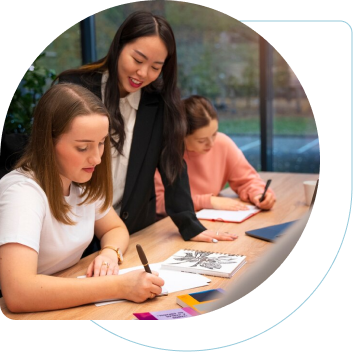 Group of three women writting on their notebooks working together on a desk