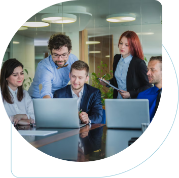 A team working together in an office room, actively discussing with their computers and notebooks